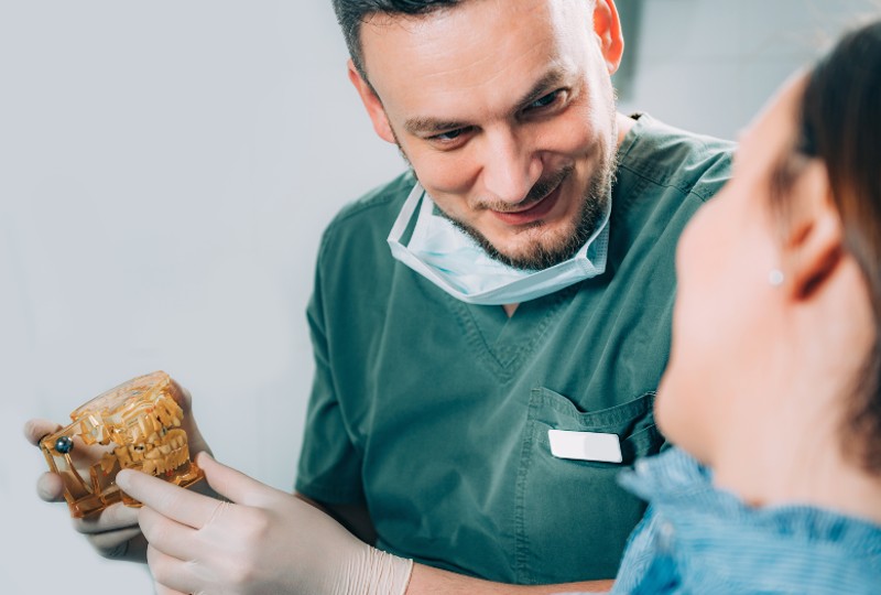 Dentist showing a dental model to a patient, highlighting implant recovery phases.